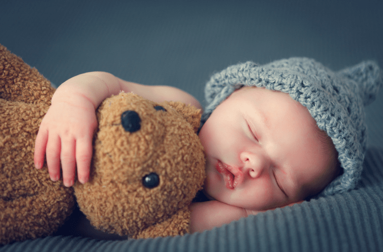 Bebek Uyku Eğitiminde Doğru Bilinen Yanlışlar başlıklı makalede kullanılan, oyuncak ayısına sarılmış bir şekilde uyuyan bebek